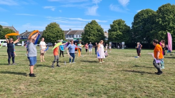 A group of players standing in a field waving coloured cloth above their heads during a class