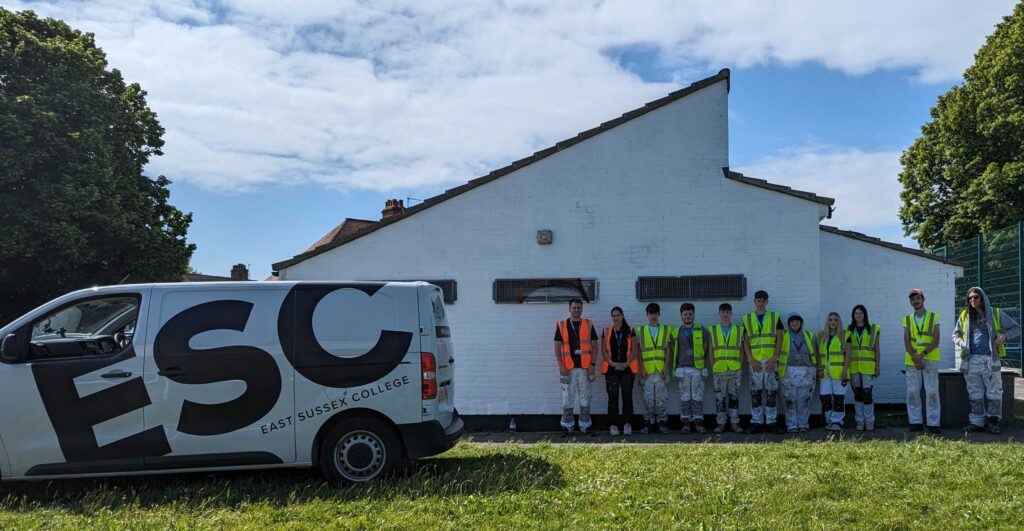 East Sussex College's Level 2 Painting and Decorating students and their teachers standing next to our Inclusion Hub after painting the walls white.